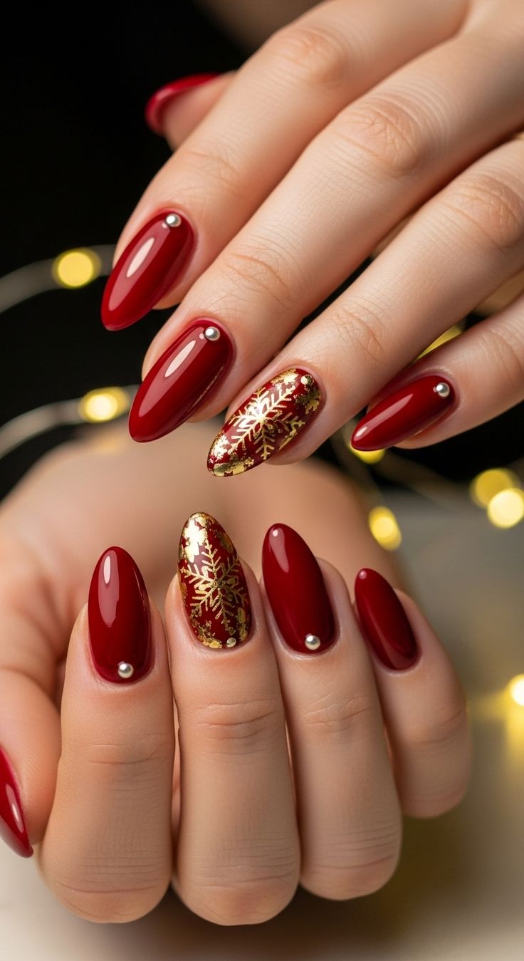 Stunning almond-shaped red nails with delicate gold snowflak