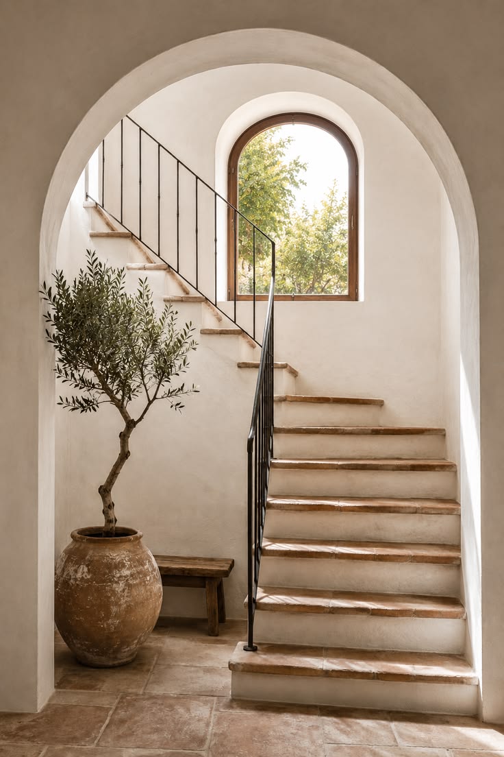 A warm Mediterranean staircase with a large plaster arch, te