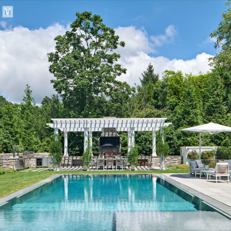 This poolside pergola features a kitchen with grills, a pizz