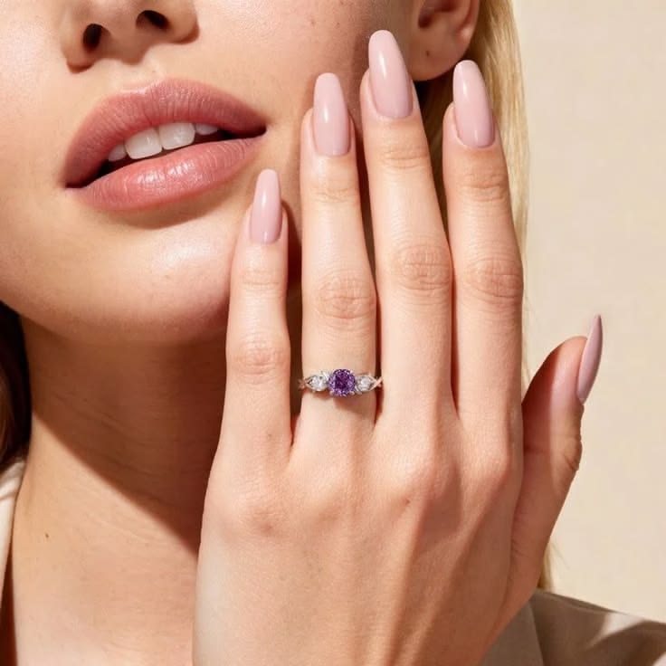 A rose-cut purple gem glows between two white stones, restin