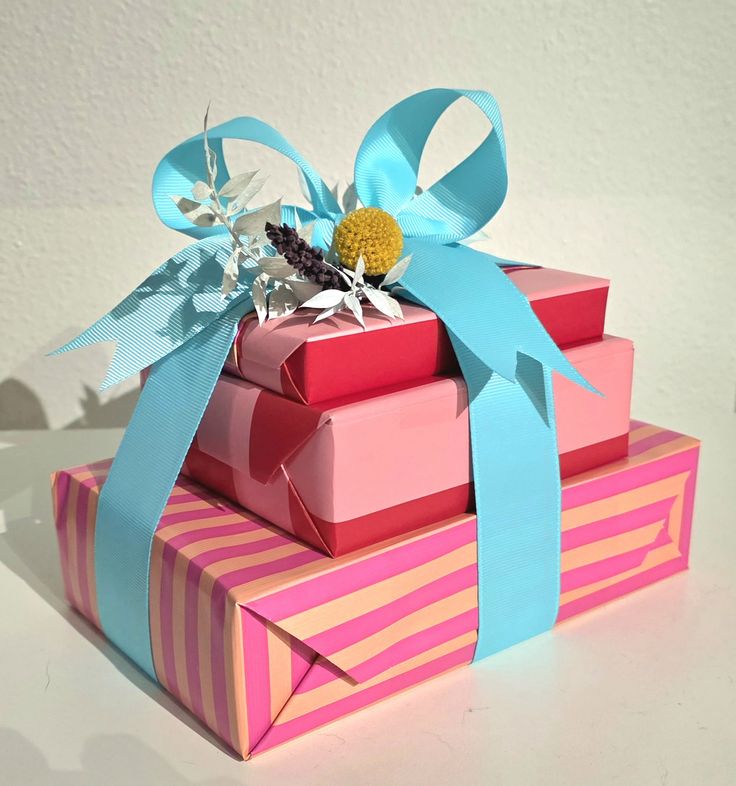 Pink wrapping paper and blue grosgrain ribbon stacked birthd