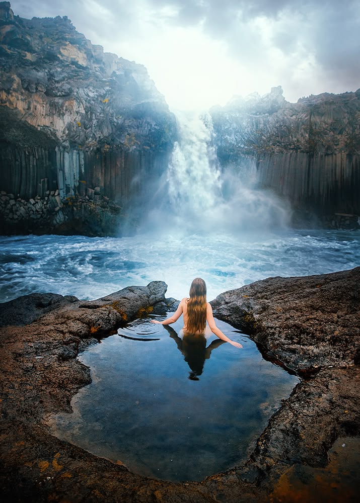 Woman sitting in pool next to a waterfall at one of the hidd