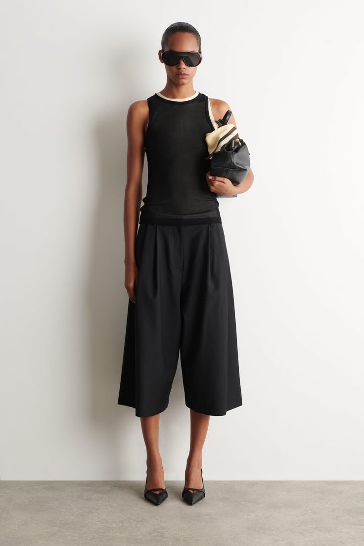 A black sheer sleeveless top featuring white and beige trim 