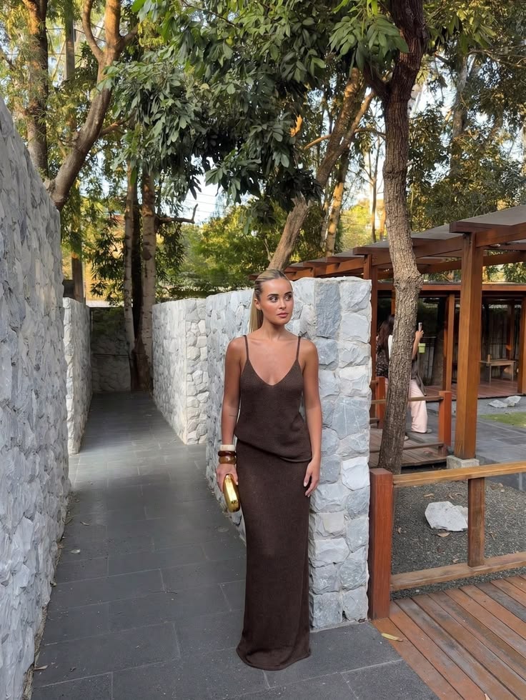 A long brown sleeveless dress shapes this serene sunset‑chic
