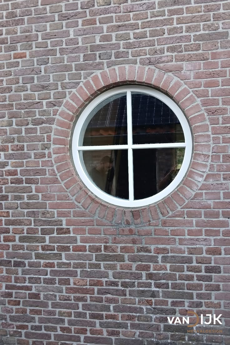 Een rond stalen raam in een bakstenen gevel is een detail da