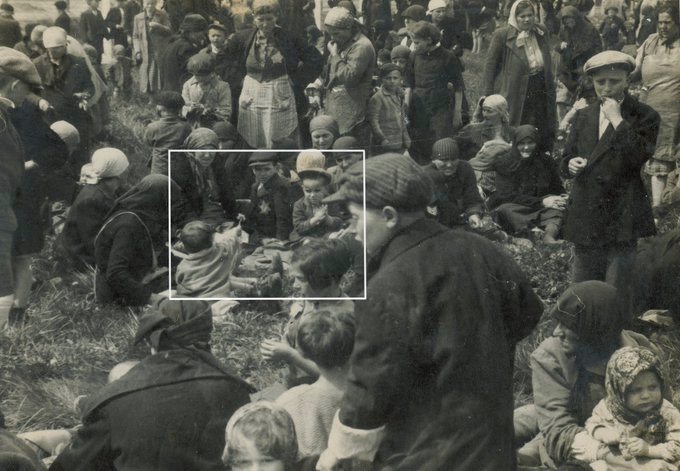 A heart-breaking moment saved in an SS picture of deportations of Hungarian Jews at Auschwitz II-Birkenau. It was taken 79 years ago, most likely in late May 1944. 

A little child found a dandelion in the grass and is handing it or showing it to an older boy. All the people in 